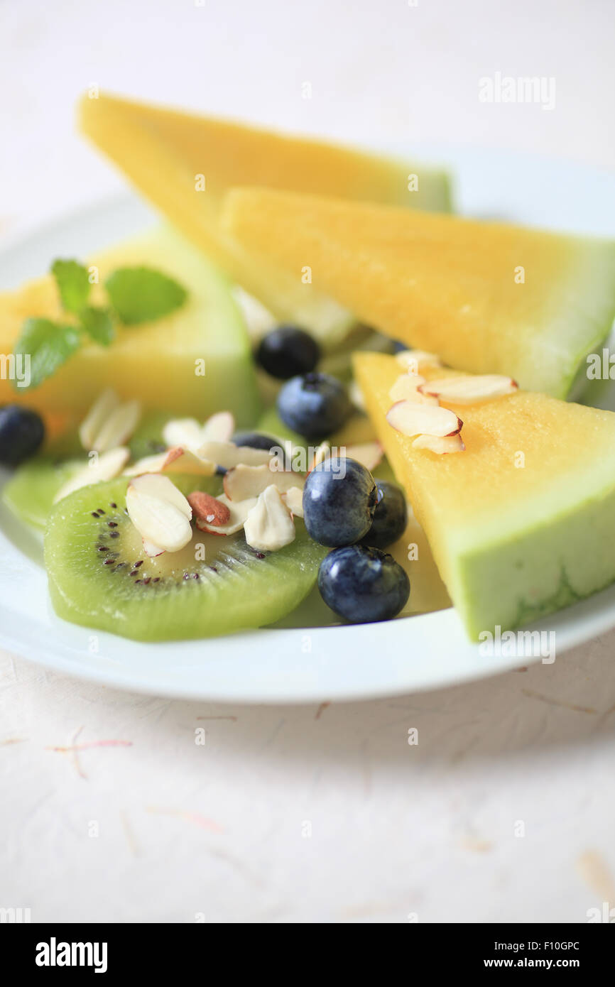 Fresh yellow watermelon with kiwifruit, blueberries and sliced almonds, copy space included Stock Photo