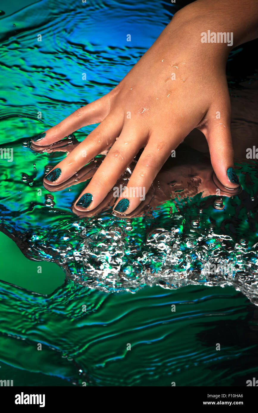 a hand with creative nail design on a green and blue water background F10HA6