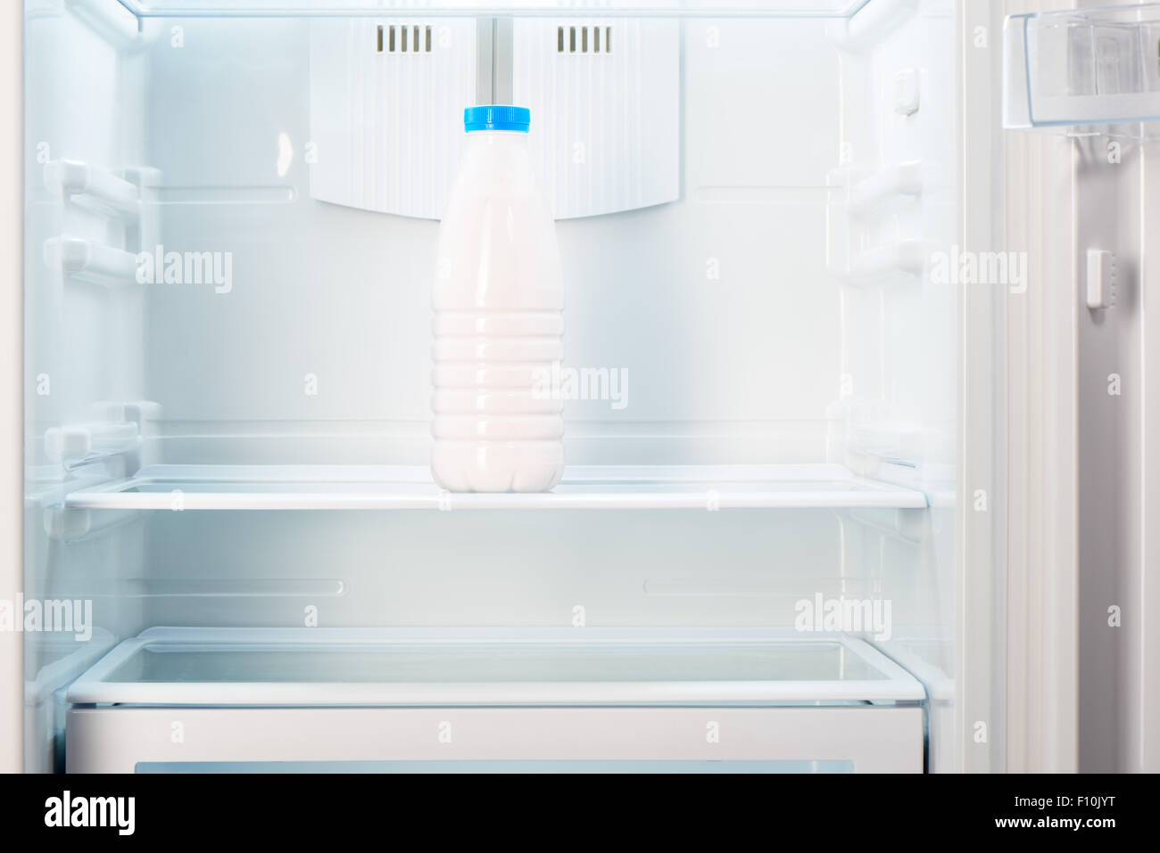 Bottle of yoghurt on shelf of open empty refrigerator. Weight loss diet