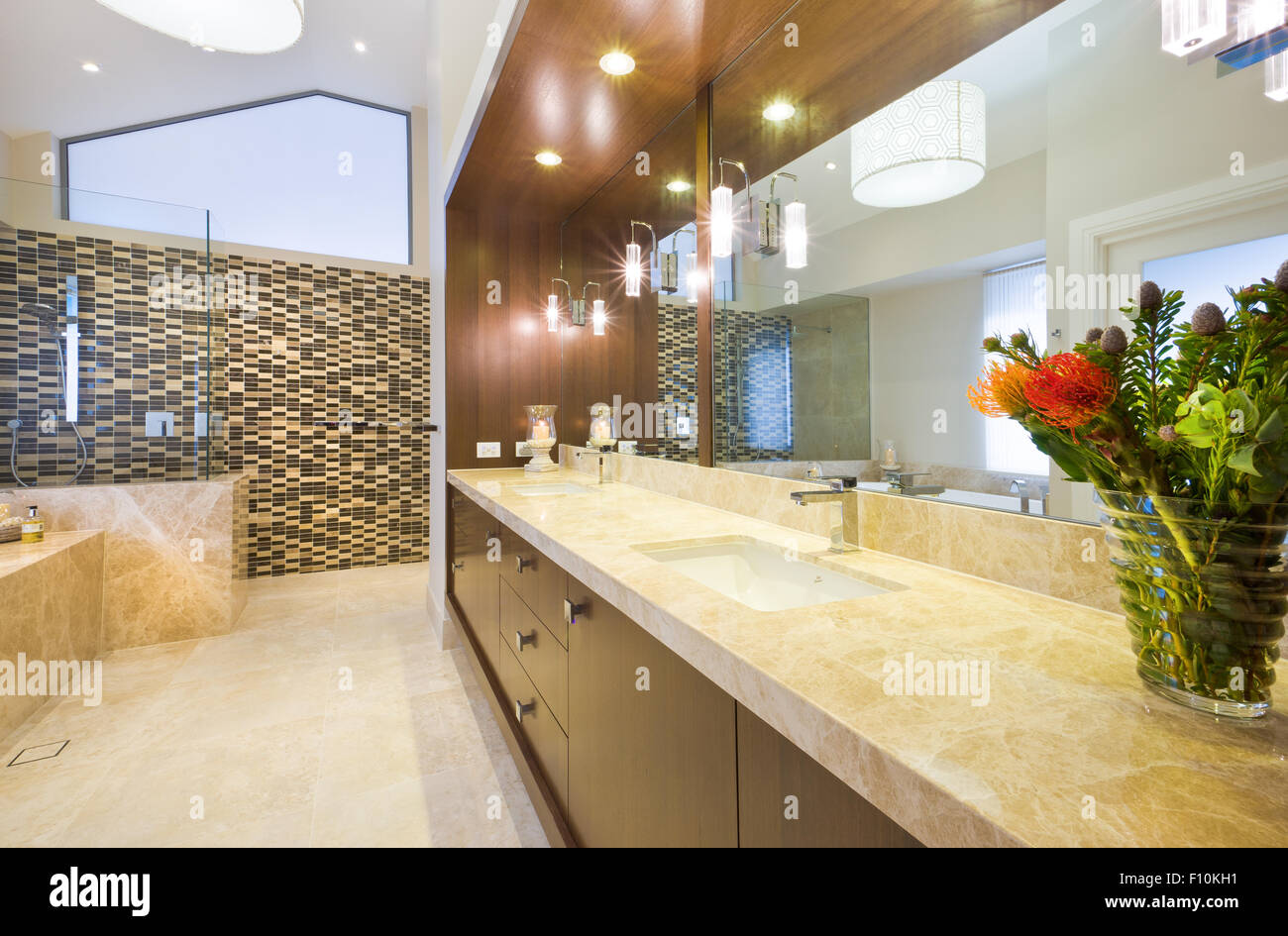 Spacious bathroom with marble floor, wooden details and a beautiful bouquet as a decor Stock Photo