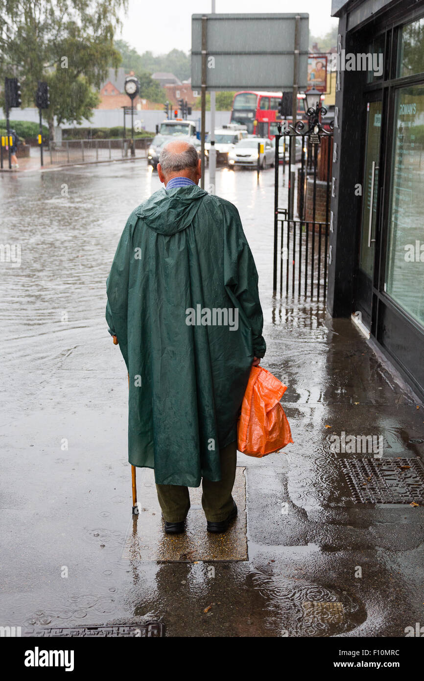 Purley, London, UK, 24th August 2015. An elderly man in a green poncho contemplates the flooded high street. A yellow flood warning for London has been issued by the Met Office. A fortnight's rain is predicted to fall in 24 hours. Credit:  Dave Stevenson/Alamy Live News Stock Photo