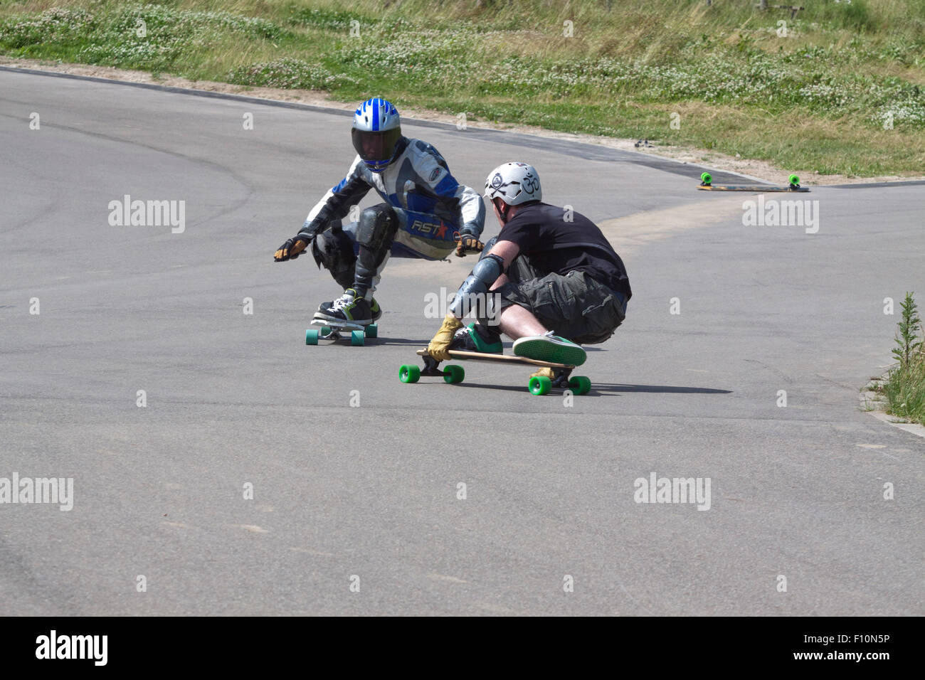 As the result of a previous crash (note the abandoned skateboard top right)  two downhill skateboarders are on a collision course Stock Photo - Alamy