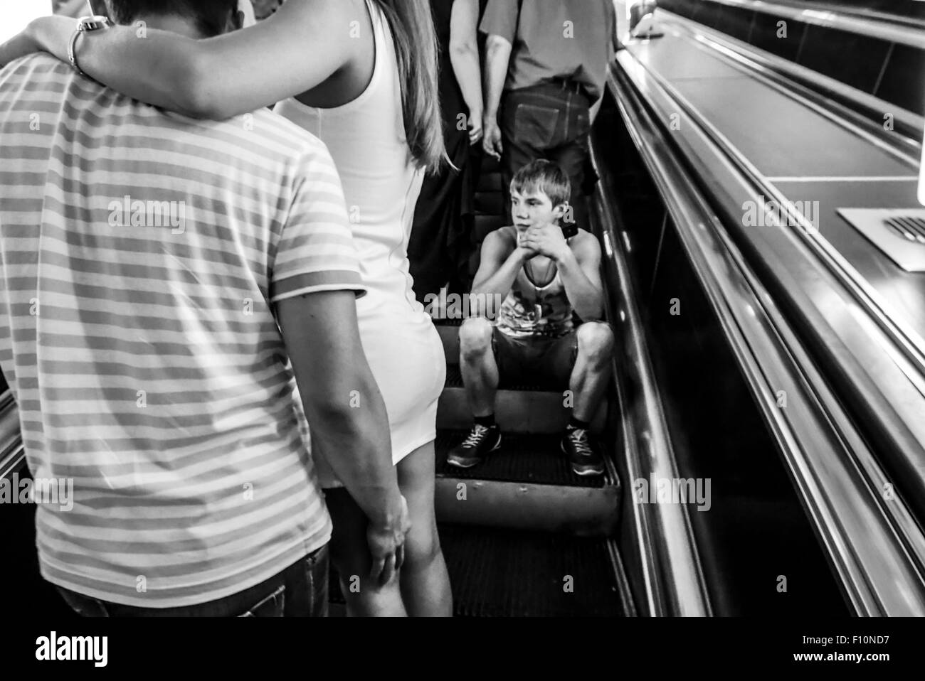 Kiev, Ukraine. 24th Aug, 2015. Lonely boy is sitting on the escalator, riding up to the Independence Square station. On the front and the background are two embracing couples. -- Thousands of Ukrainians celebrate the 24 anniversary of Independence of Ukraine mass festivities in towns and villages across the country. This holiday marred by Russian aggression in the east of Ukraine and the occupation of the Crimea. Ukrainians are hoping that 25 Independence Day they will meet in a more peaceful environment. © Igor Golovnov/Alamy Live News Stock Photo