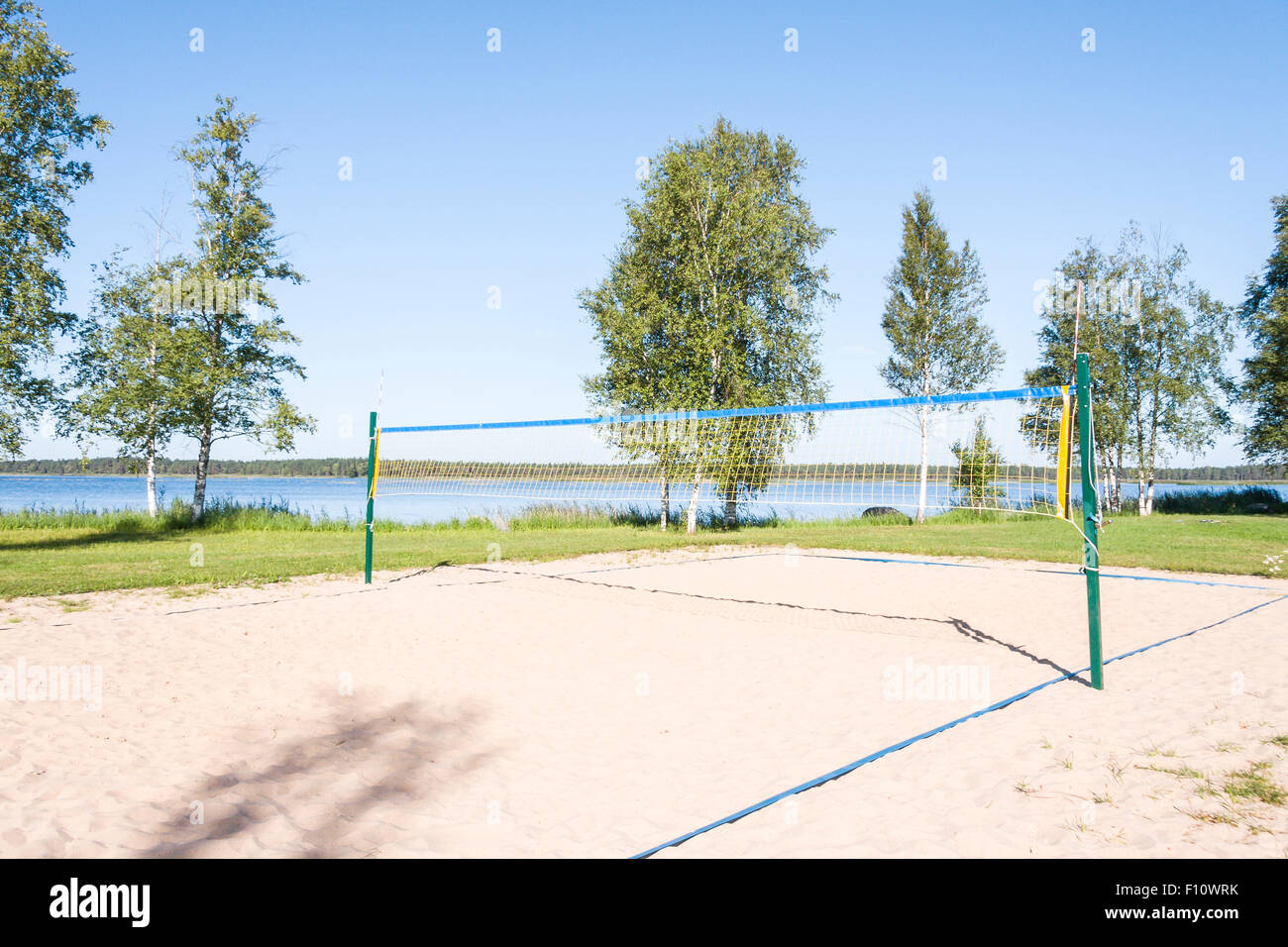 Sandy volleyball field at a lake coast surrounded by grass in a sunny summer day Stock Photo