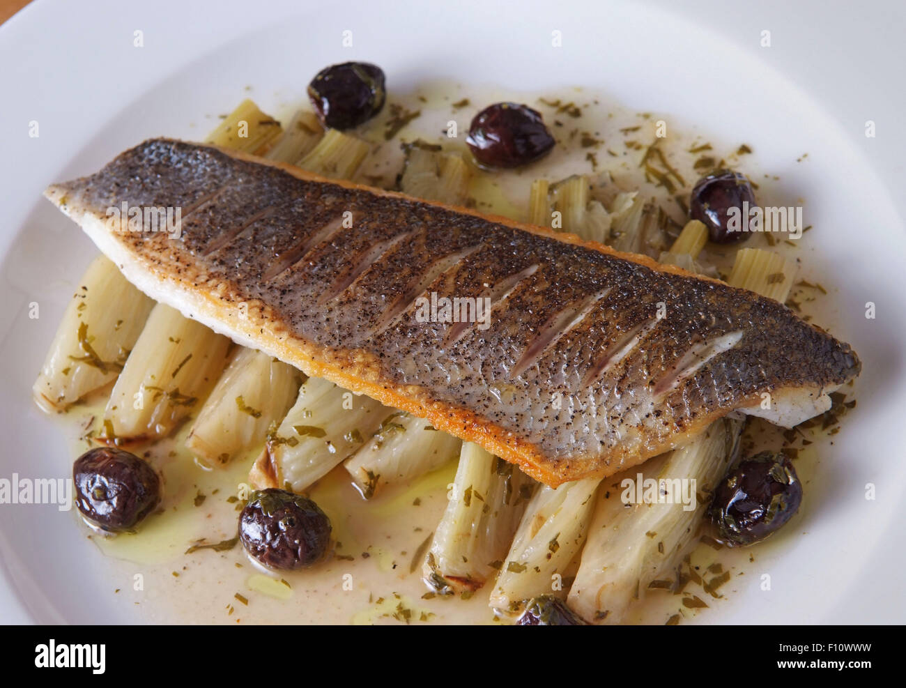 Pan fried sea bass, black olives & herb fennel. Stock Photo