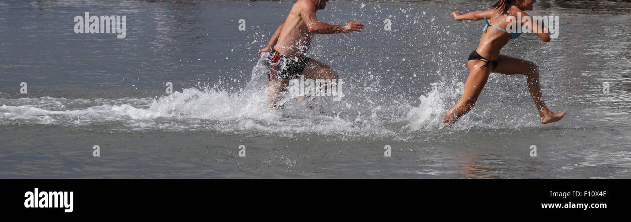 two peoples legs  running through the waves Stock Photo