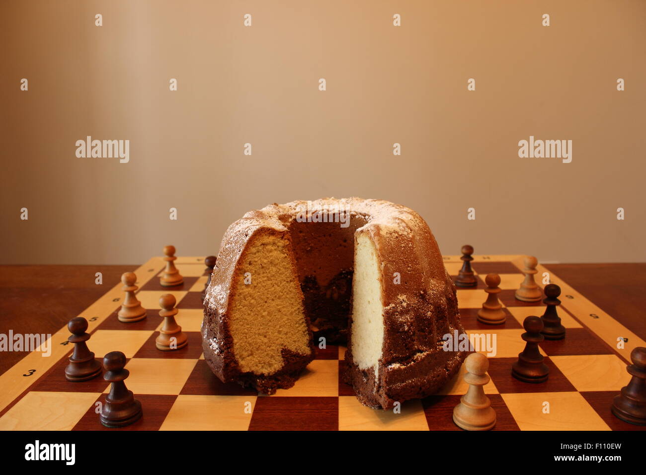 cake on chessboard surrounded by chessmen Stock Photo