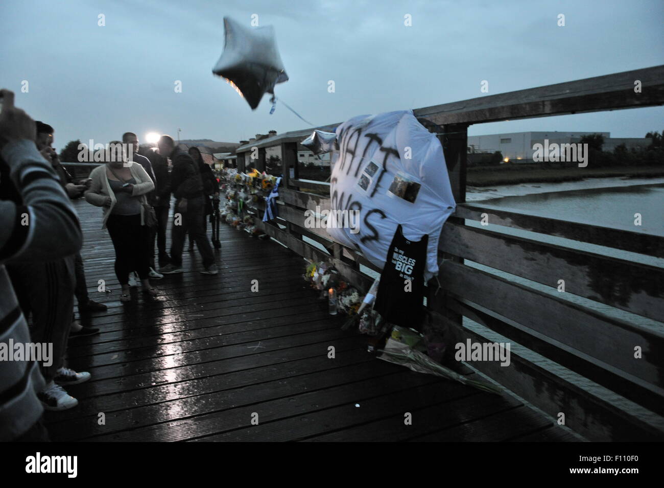 Shoreham, Sussex, UK. 24th August, 2015.  Friends of Matt Jones a personal trainer from Littlehampton who was one of the Shoreham Air Disaster victims gather on the old toll bridge near the crash scene this evening to pay their respects Eleven people are believed to have dies after a Hawker Hunter jet flown by Andrew Hill crashed on to the A27 during a display at the Shoreham Airshow last Saturday  Credit:  Simon Dack/Alamy Live News Stock Photo