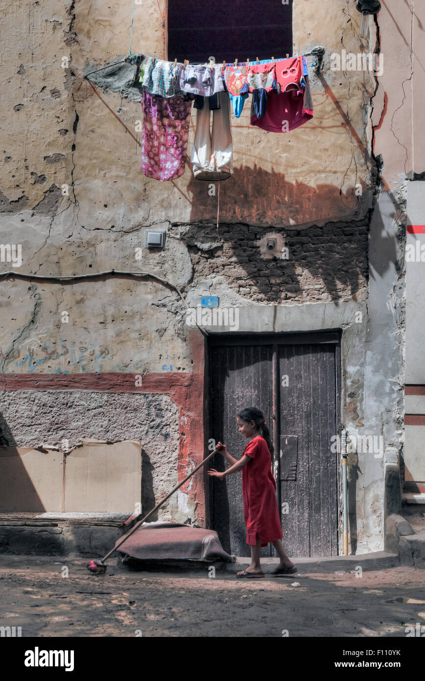 young girl sweeping the ground in the old Arabic city of Aswan, Egypt, Africa Stock Photo