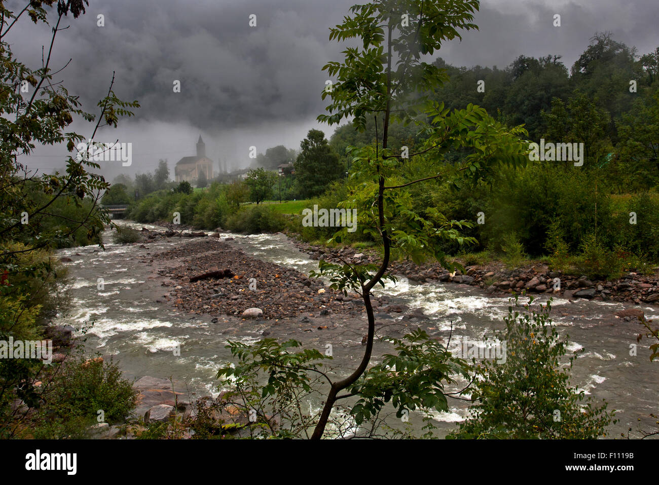 View of the river and church of Chironico on a wet, misty day. Stock Photo