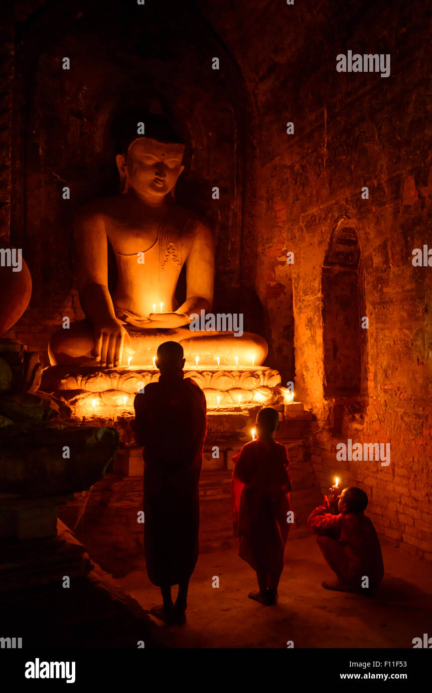 Asian monks-in-training lighting candles at Buddha shrine Stock Photo