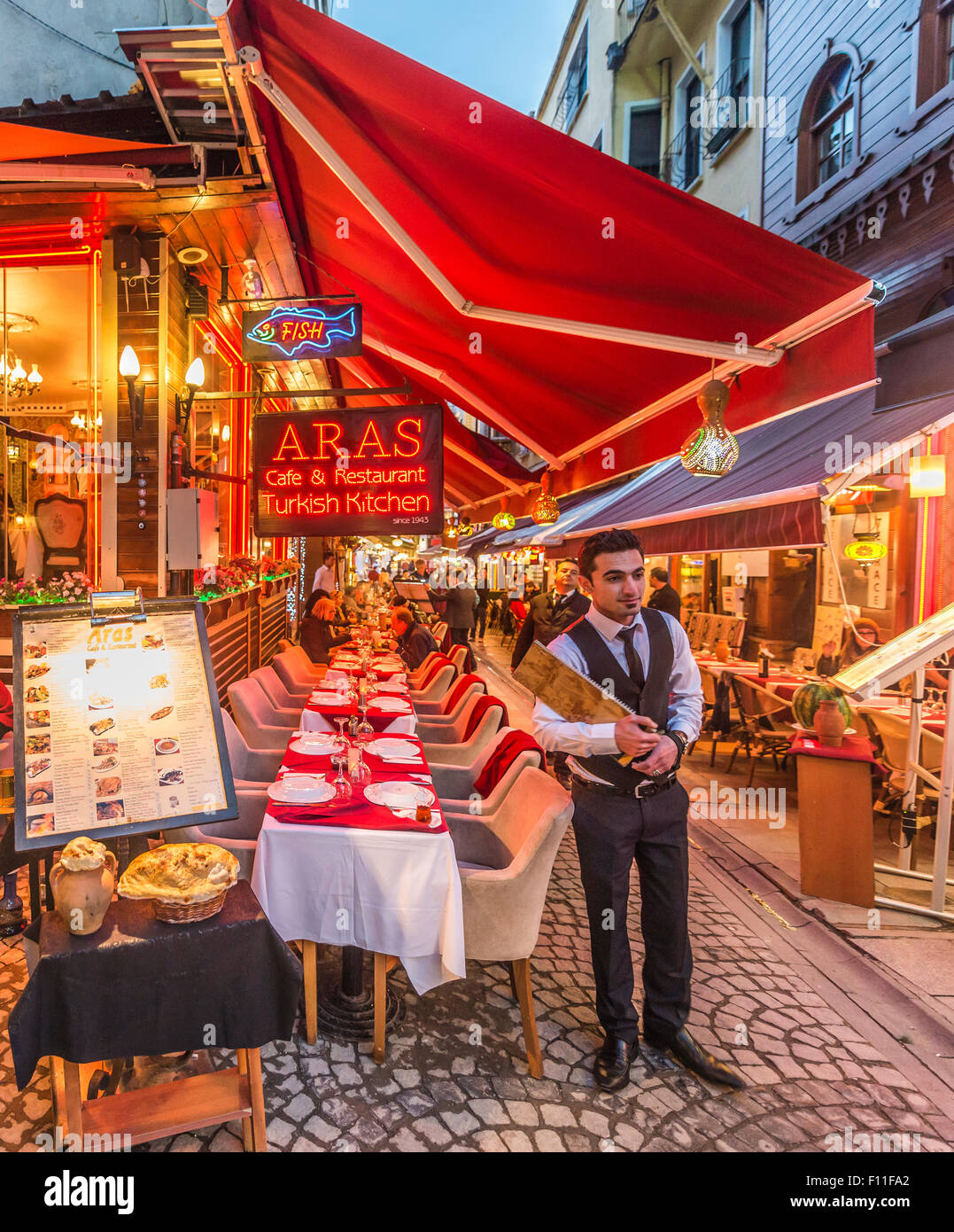 Waiter holding a menu, restaurants with outdoor tables in a pedestrian zone, European Side, Istanbul, Turkey Stock Photo
