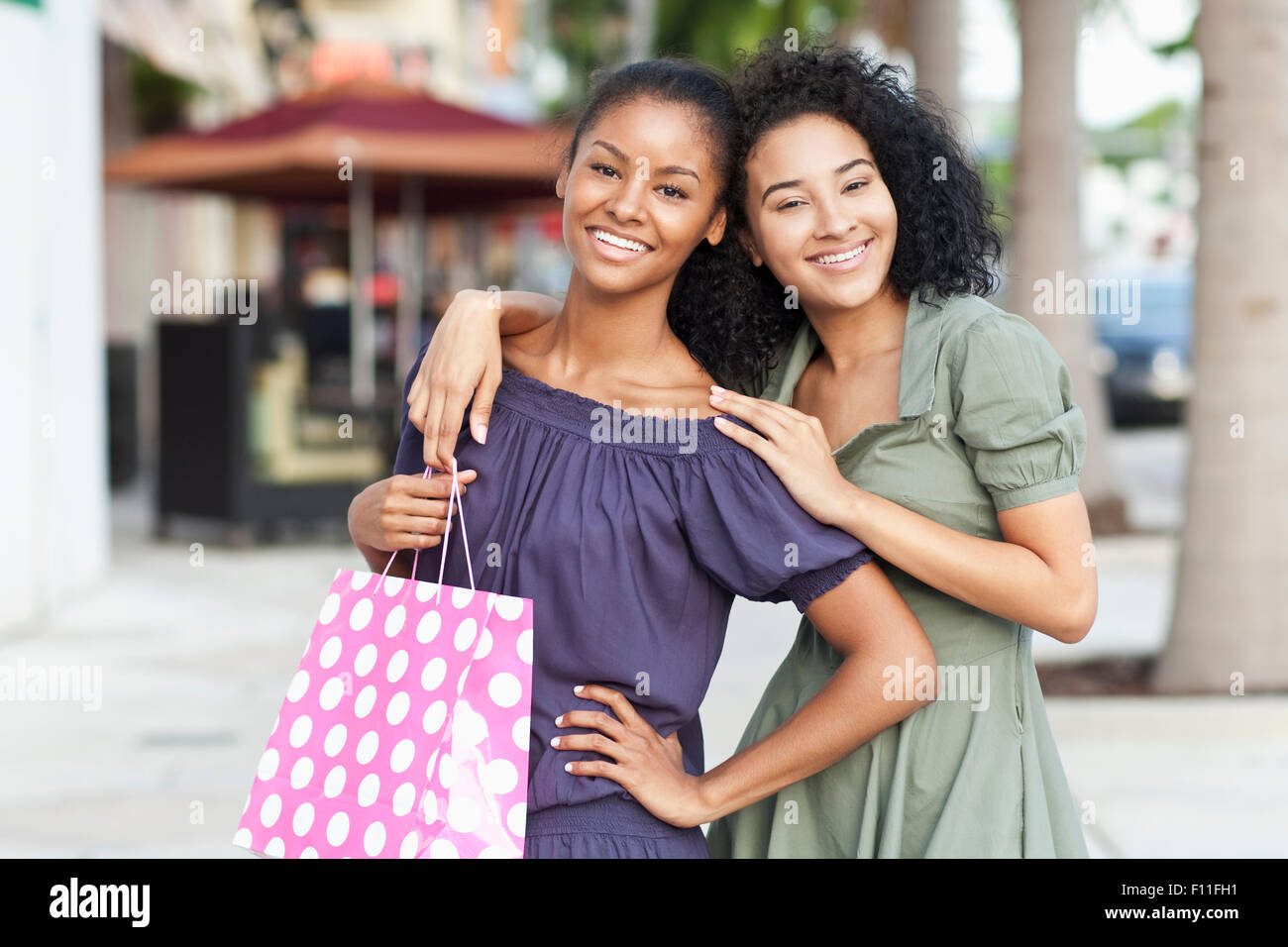 Black women smiling on city sidewalk Stock Photo