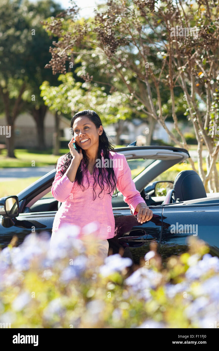 Indian woman talking on cell phone near car Stock Photo
