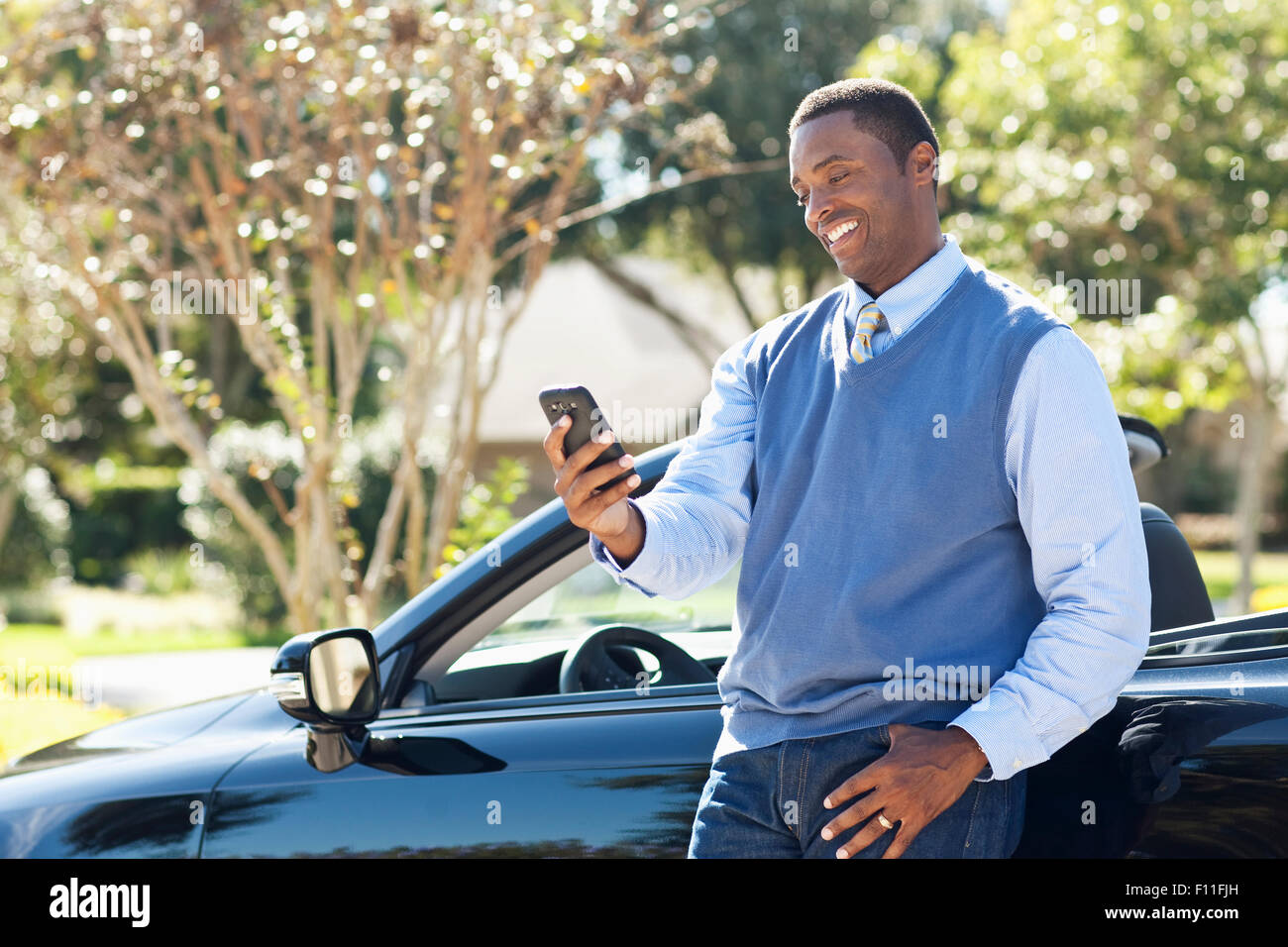 Black man using cell phone at convertible Stock Photo