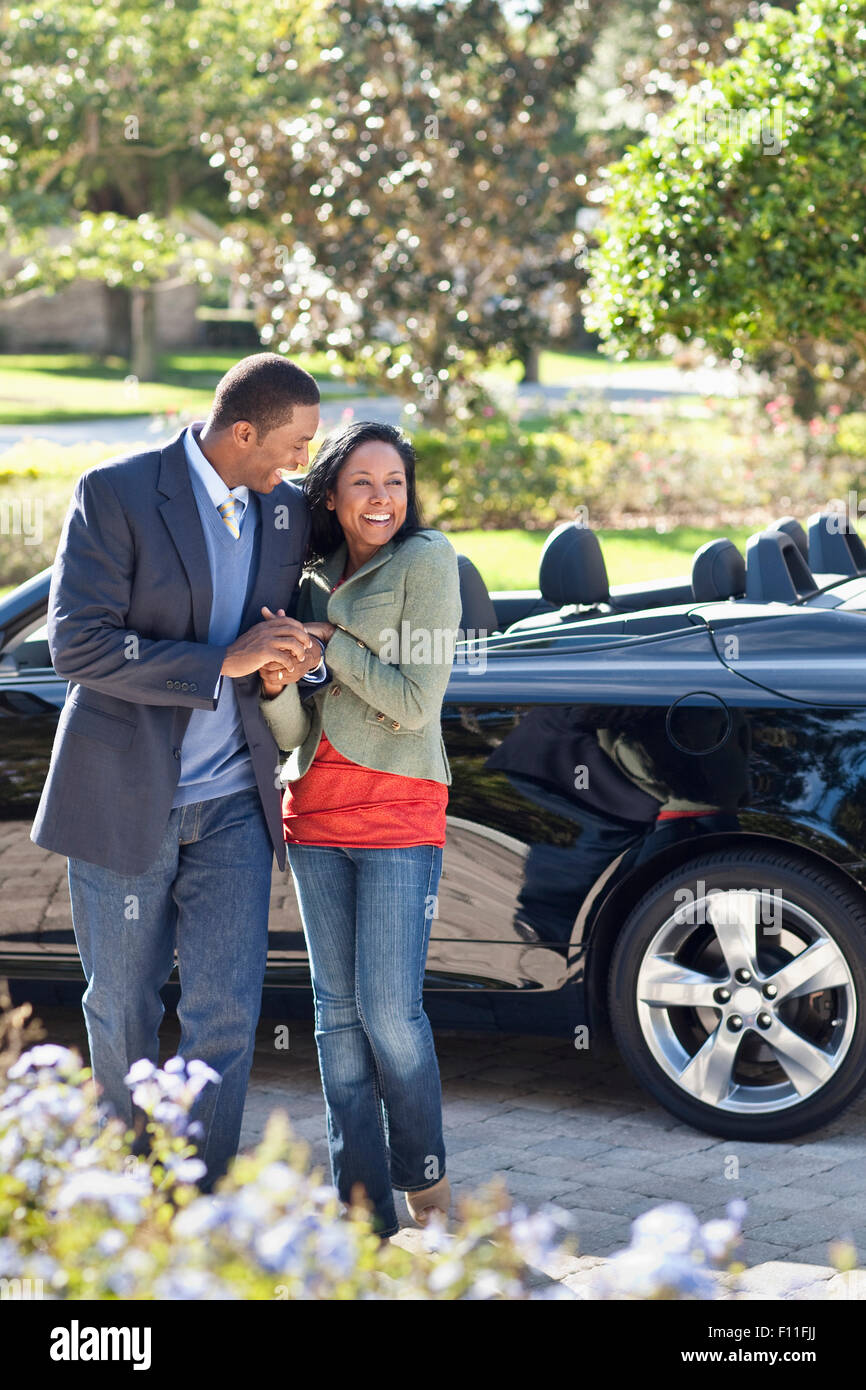 Couple walking in driveway at convertible Stock Photo