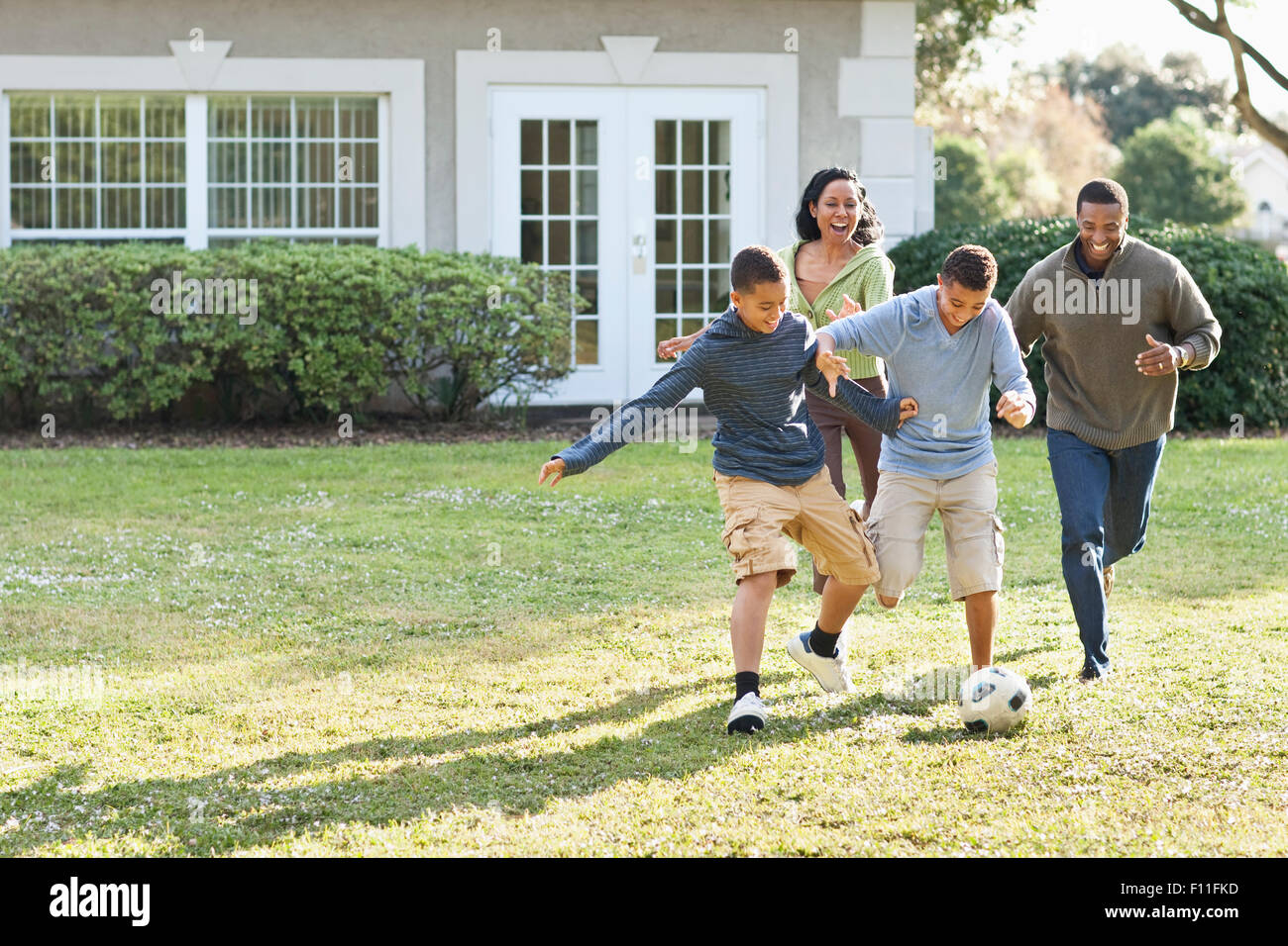 Family playing soccer in backyard Stock Photo