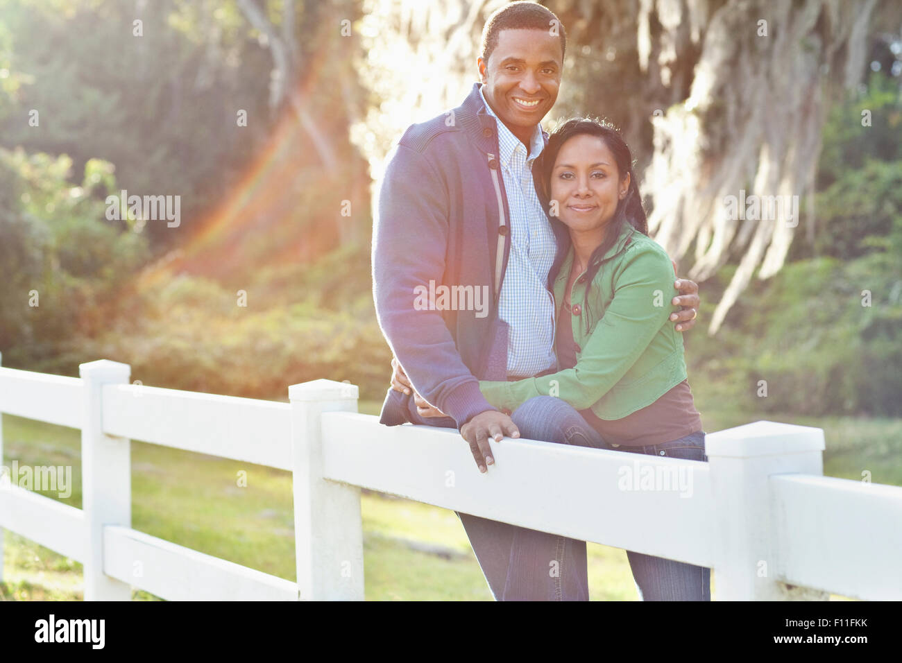 Smiling couple leaning on fence Stock Photo
