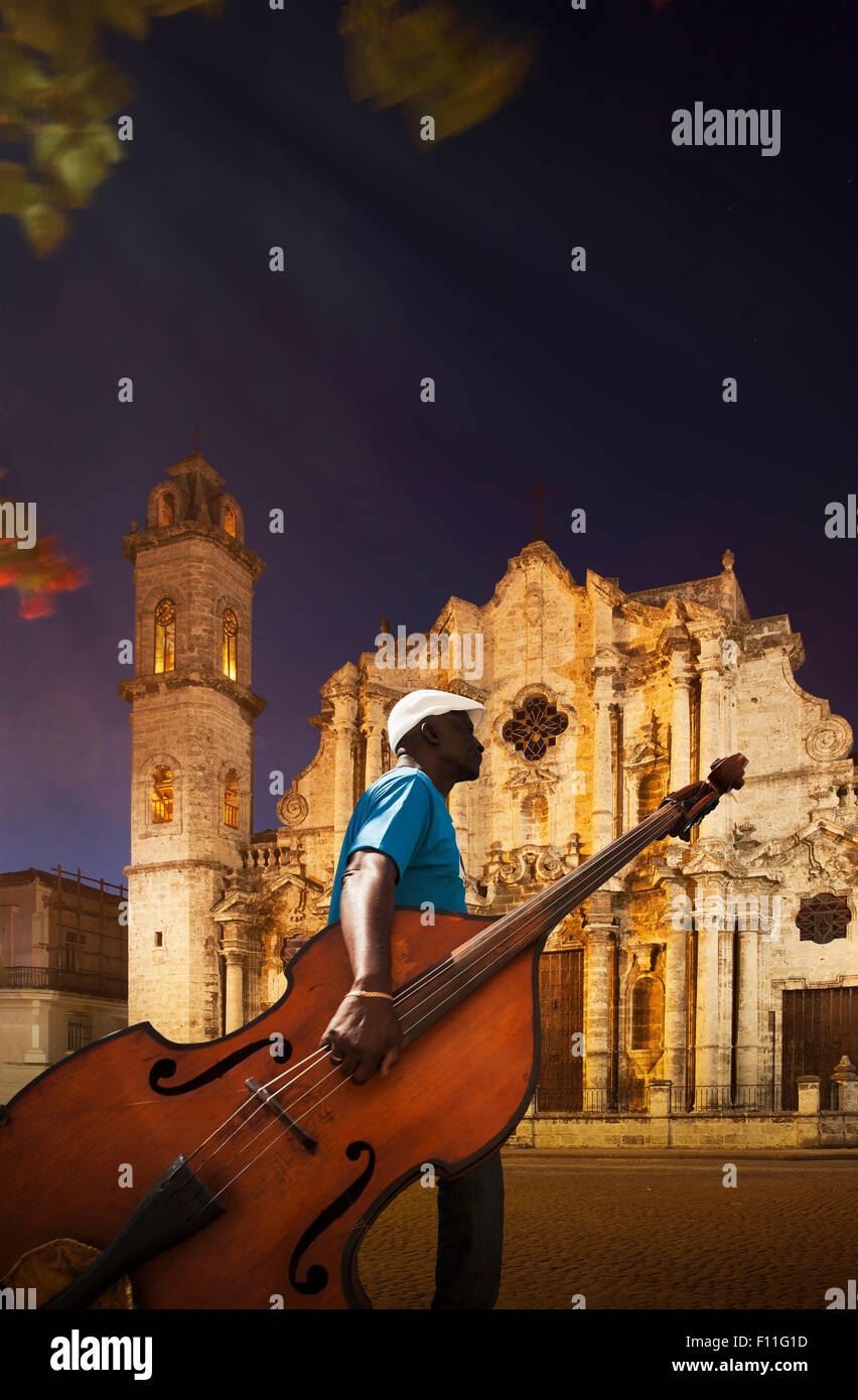 Hispanic musician carrying upright bass near church, Havana, Cuba Stock Photo