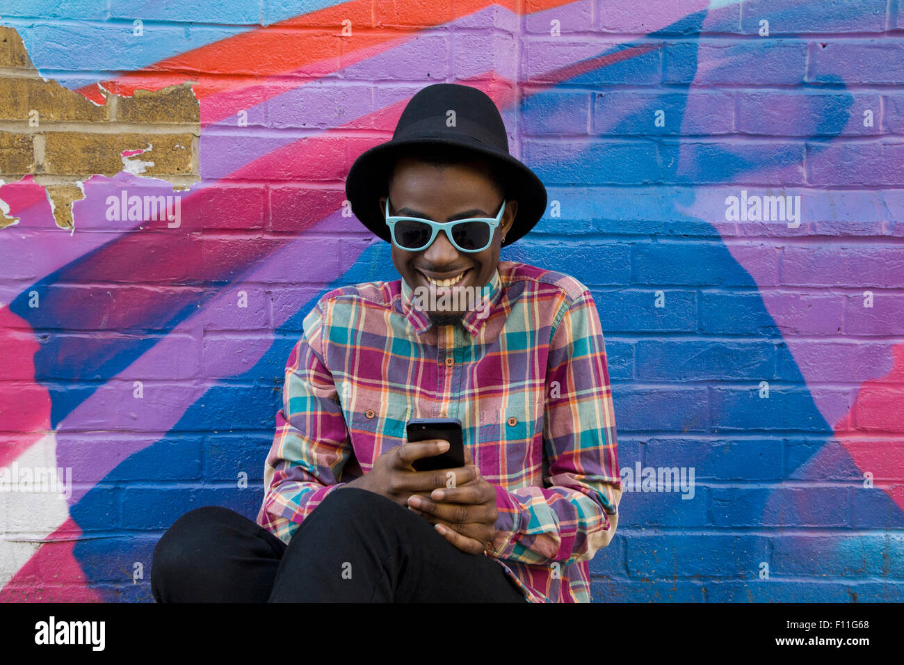 Black man using cell phone near colorful wall Stock Photo