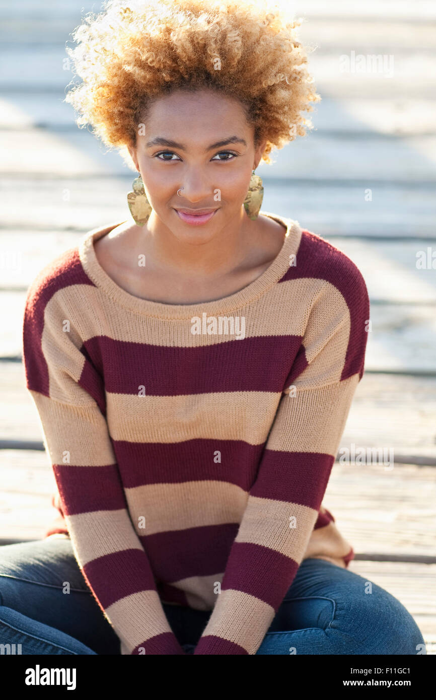Black woman sitting on wooden boardwalk Stock Photo