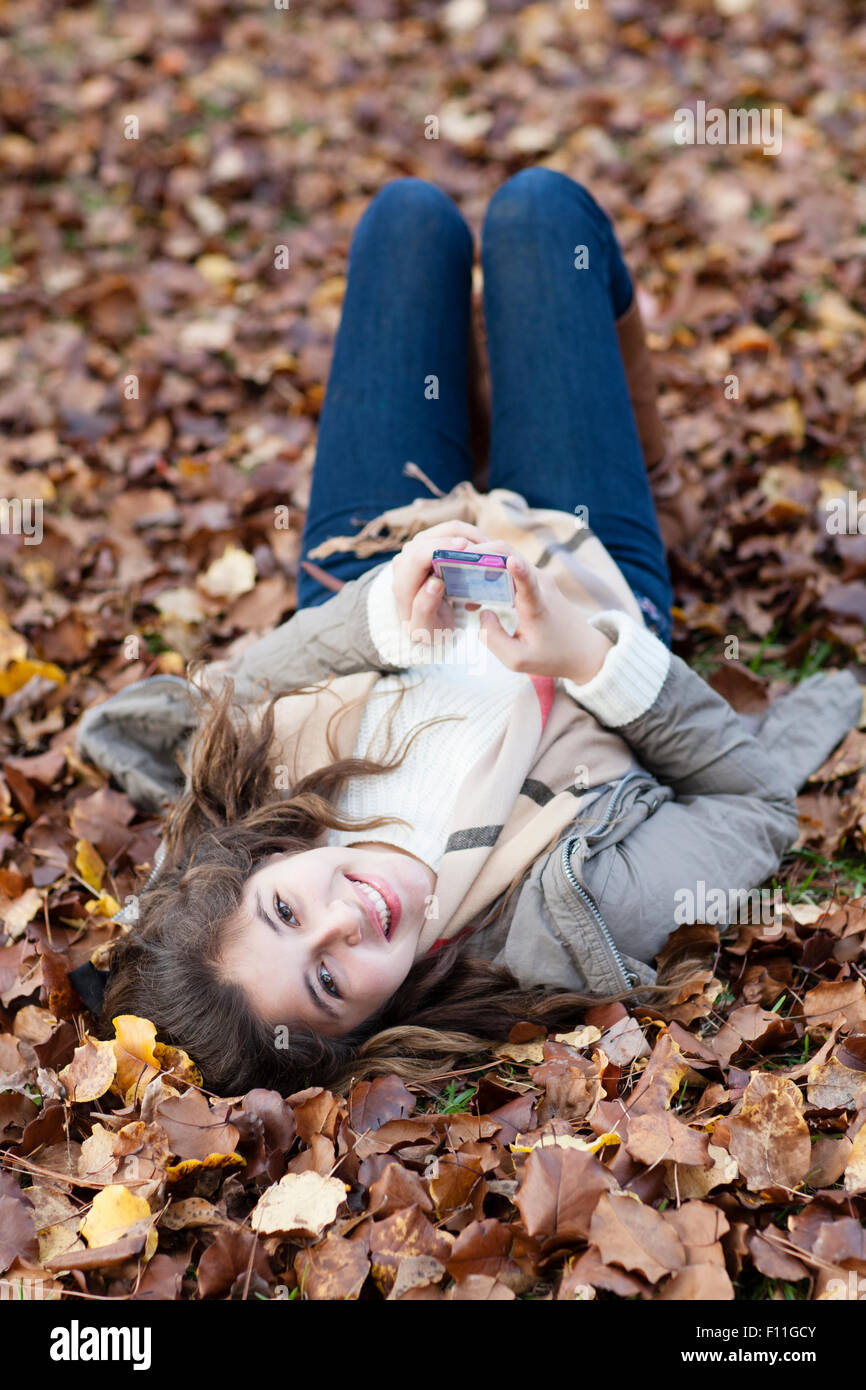 Hispanic girl laying in autumn leaves Stock Photo