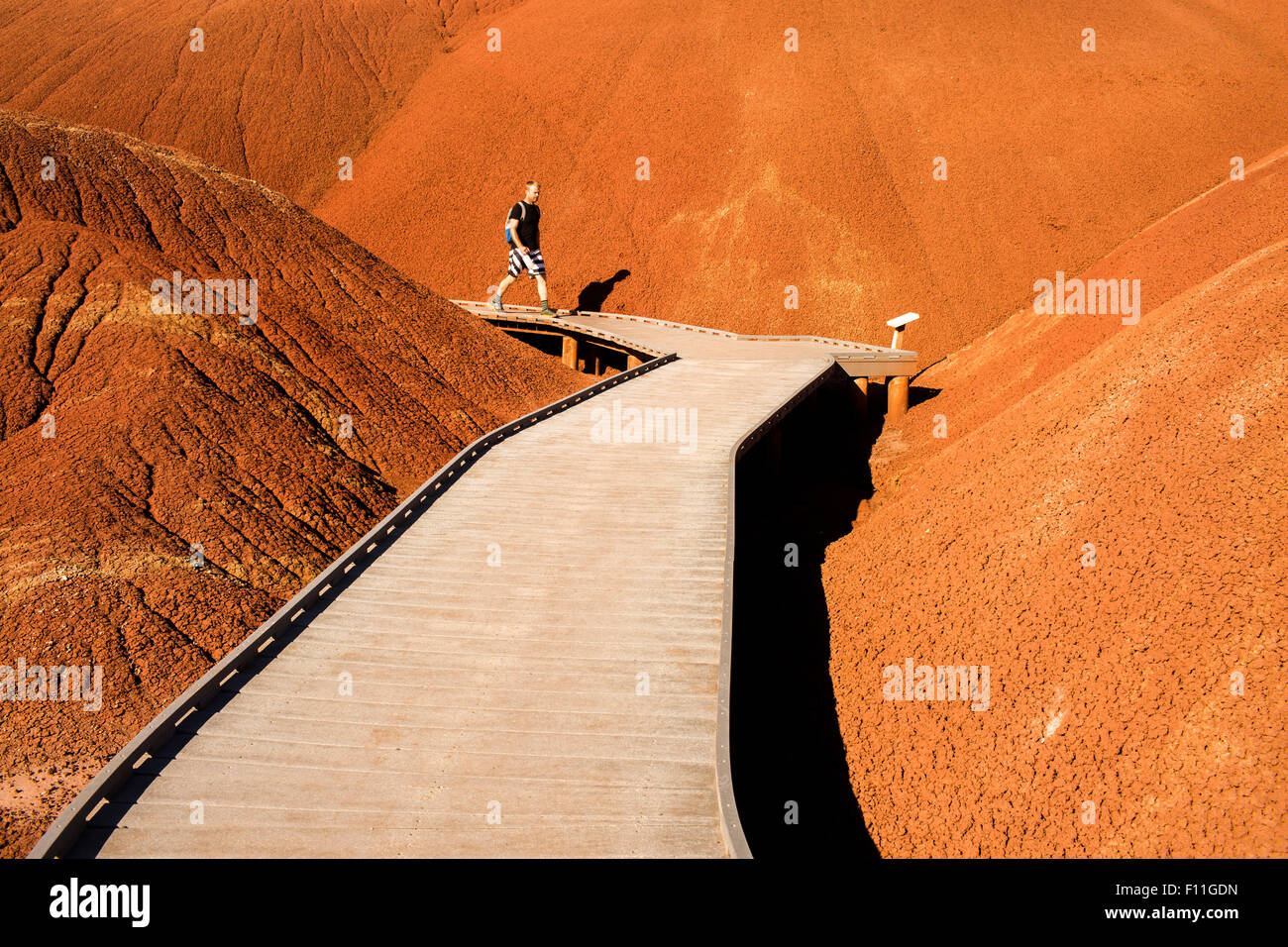 Caucasian hiker on wooden walkway in desert hills Stock Photo