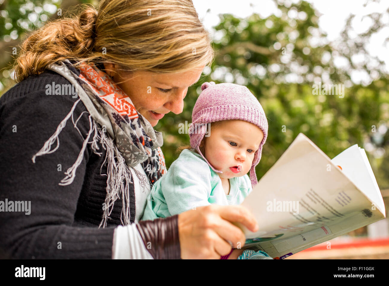 Caucasian mother and baby daughter reading in park Stock Photo