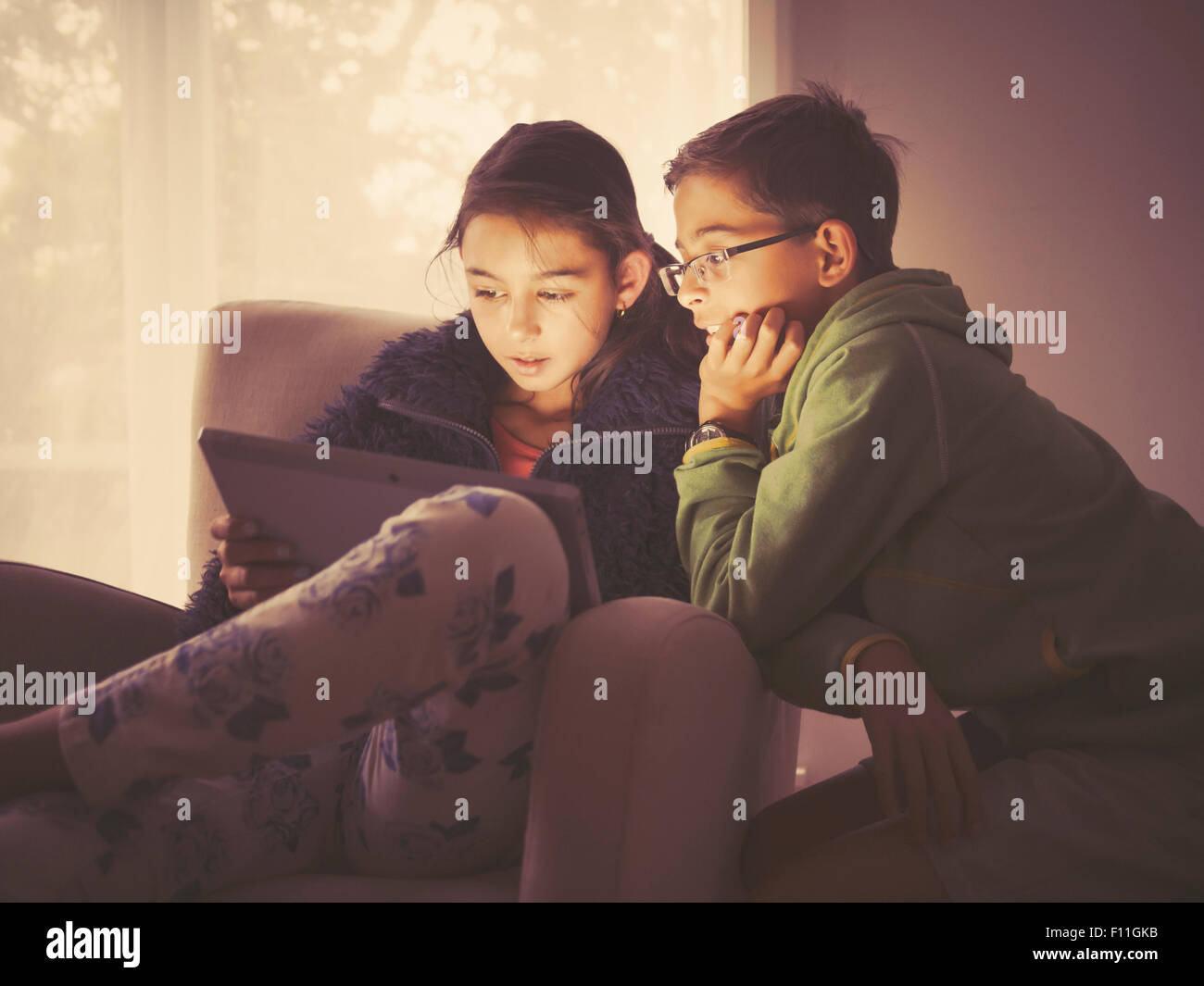 Mixed race children using digital tablet in living room Stock Photo