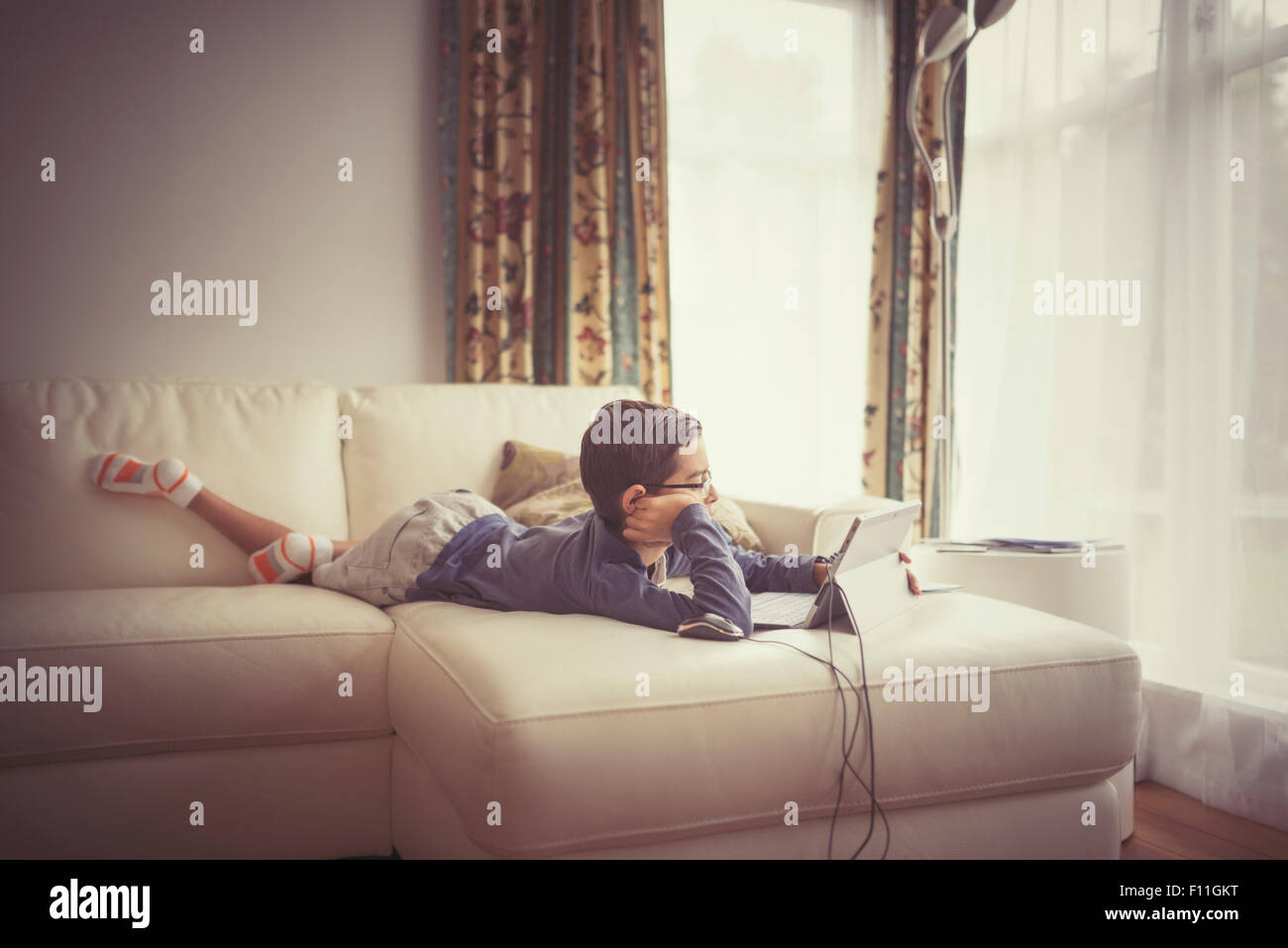 Mixed race boy using digital tablet on sofa Stock Photo