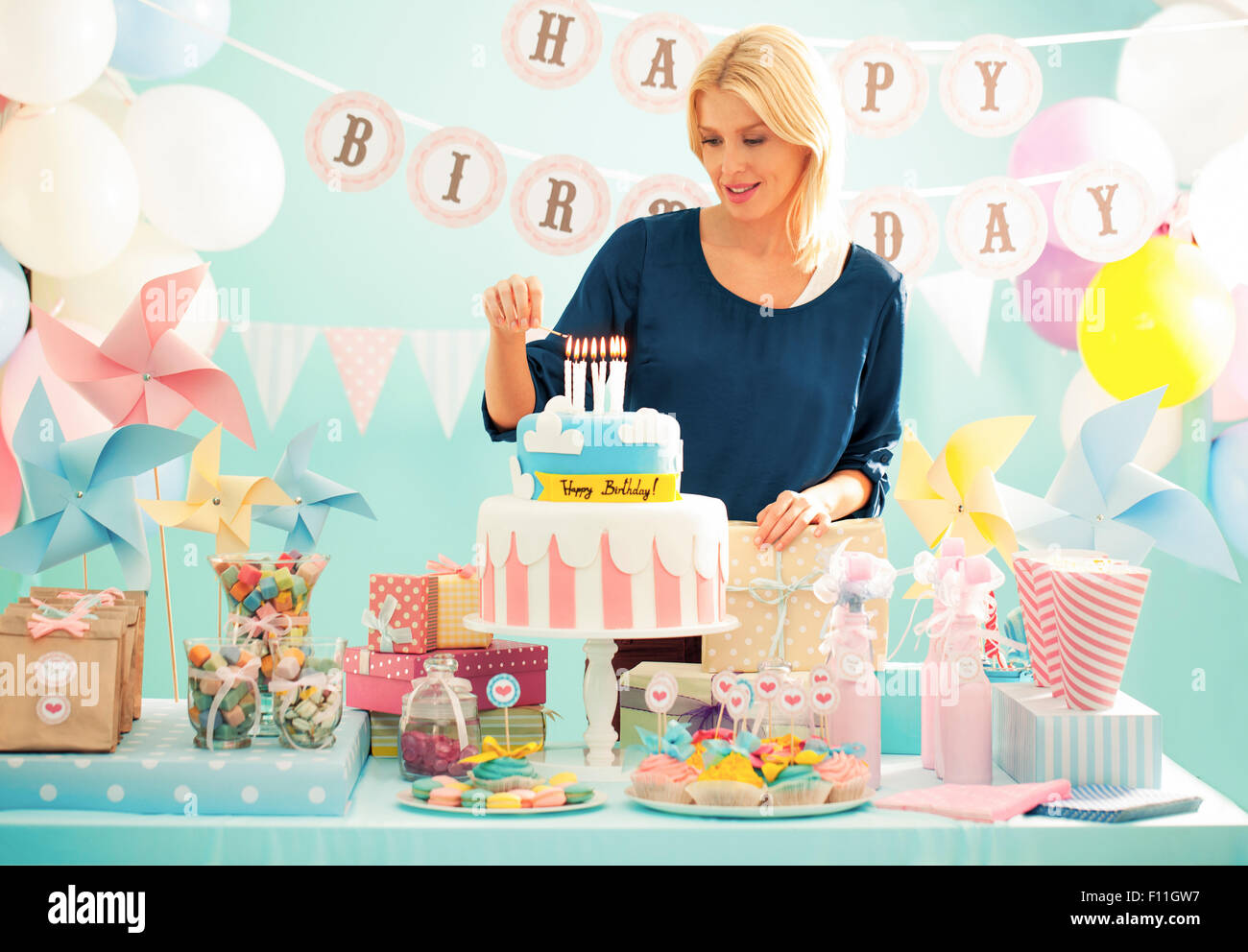 Woman lighting candles on birthday cake at party Stock Photo - Alamy