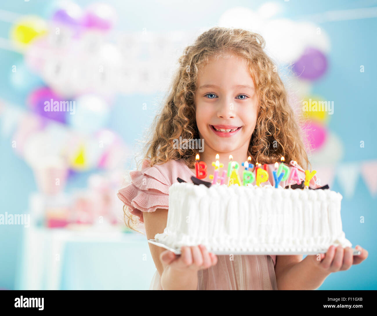 Smiling girl holding birthday cake at party Stock Photo Alamy