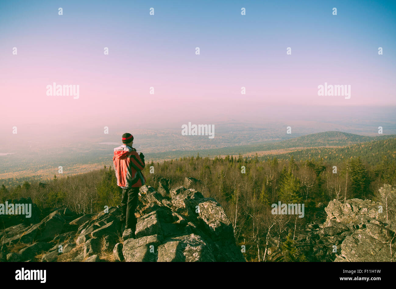 Caucasian hiker admiring view from remote rock formation Stock Photo