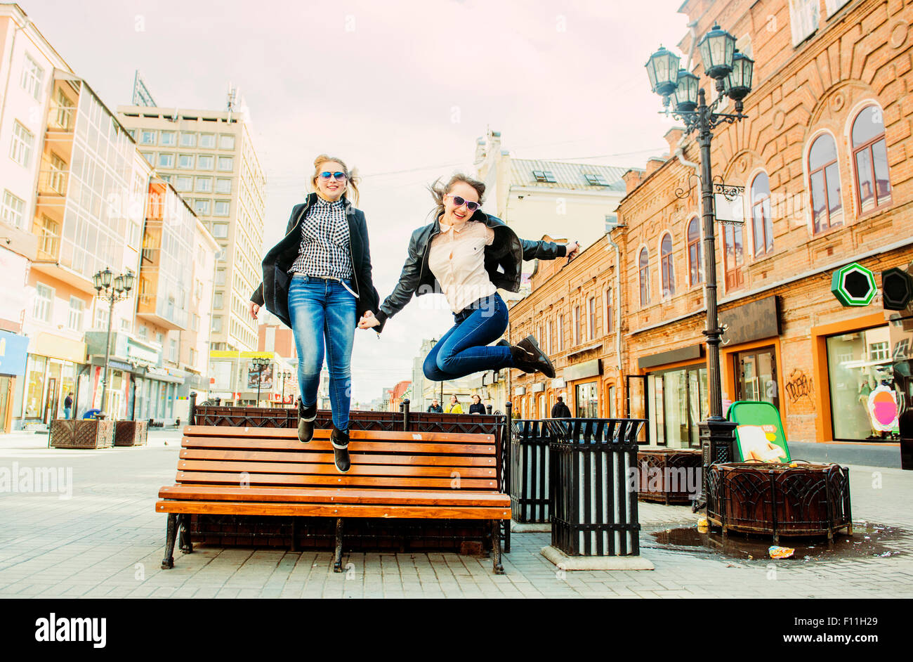 Women jumping for joy near bench Stock Photo