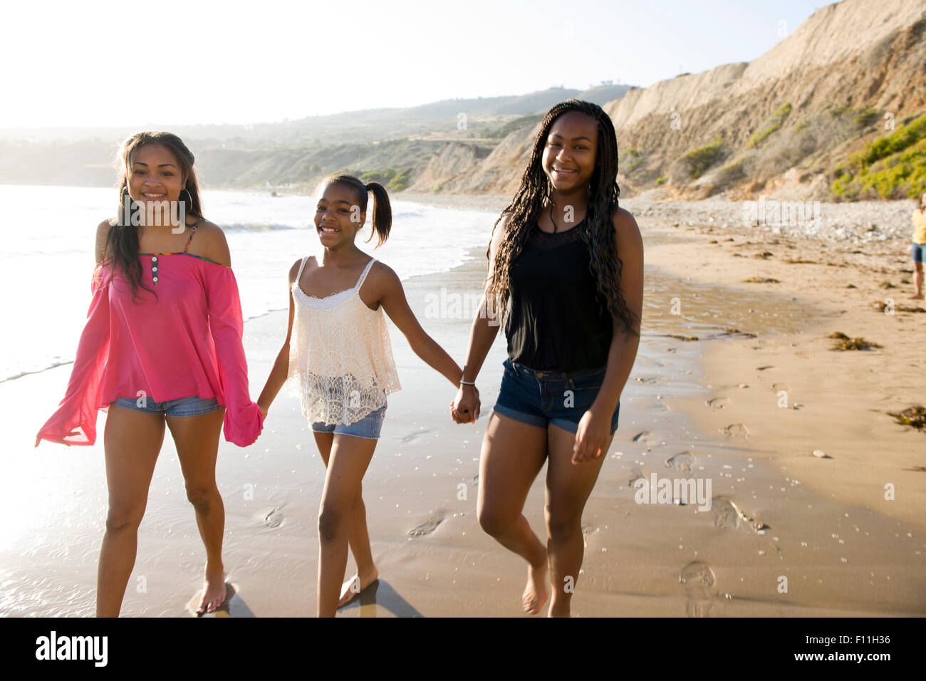 African American sisters holding hands on beach Stock Photo