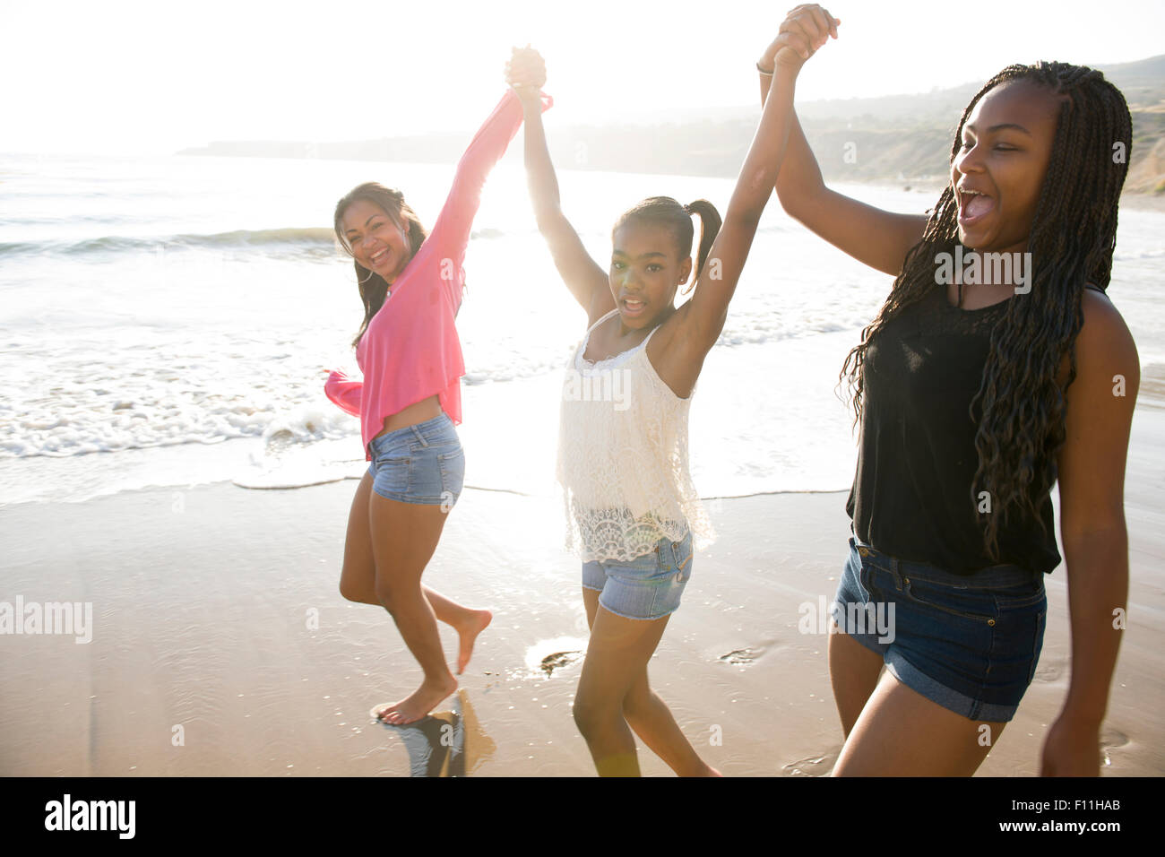 African American sisters holding hands on beach Stock Photo