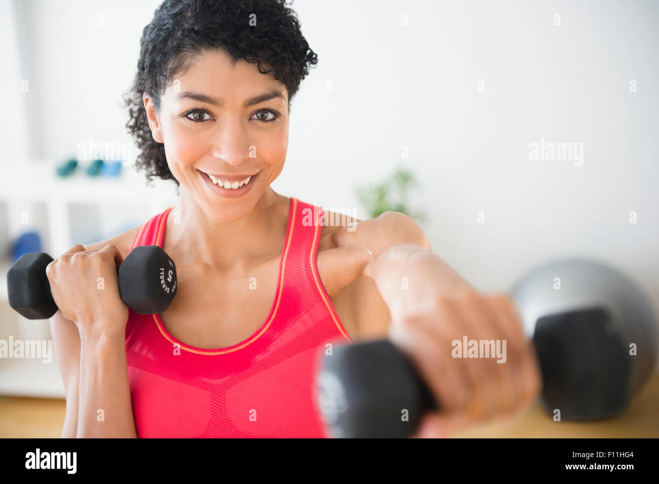 Mixed race woman lifting weights in gym Stock Photo