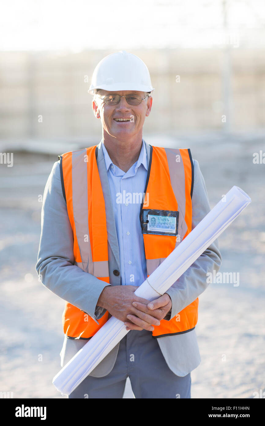 Caucasian architect holding blueprints at construction site Stock Photo