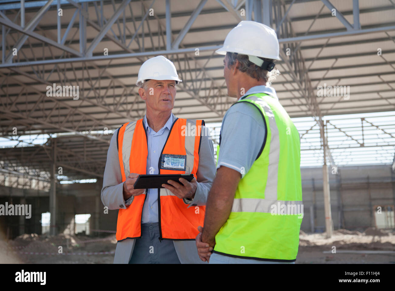 Caucasian architects talking at construction site Stock Photo