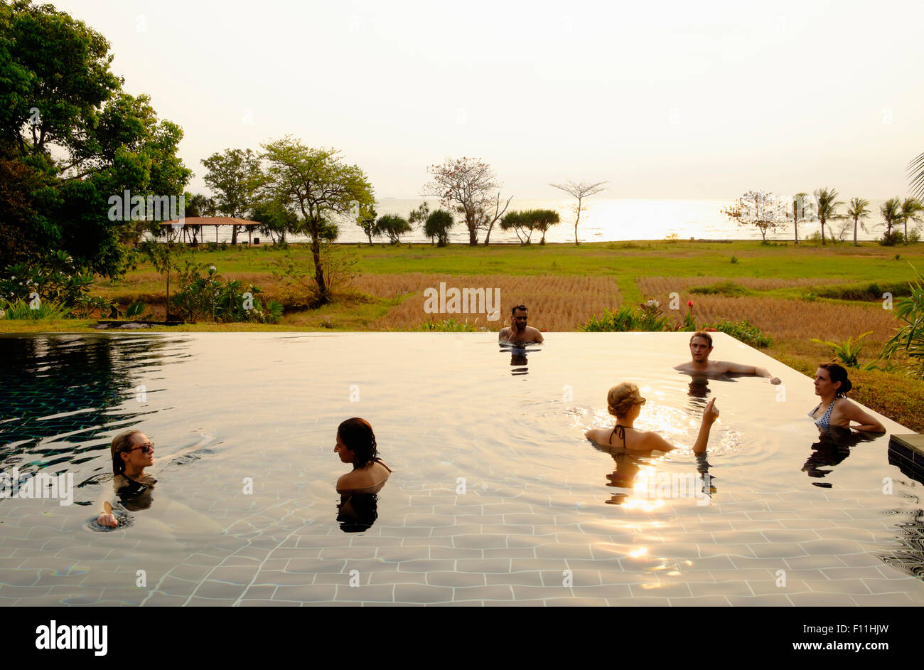 Tourists swimming in infinity pool in remote landscape Stock Photo