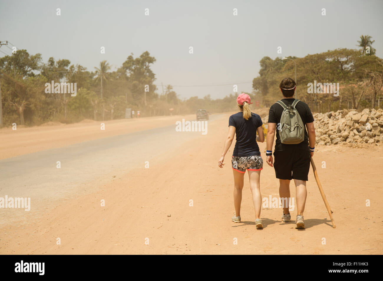 Caucasian couple walking on dirt road in remote field Stock Photo