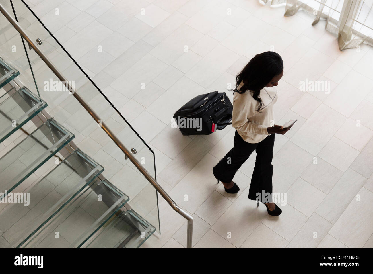 High angle view of businesswoman rolling luggage in hotel lobby Stock Photo