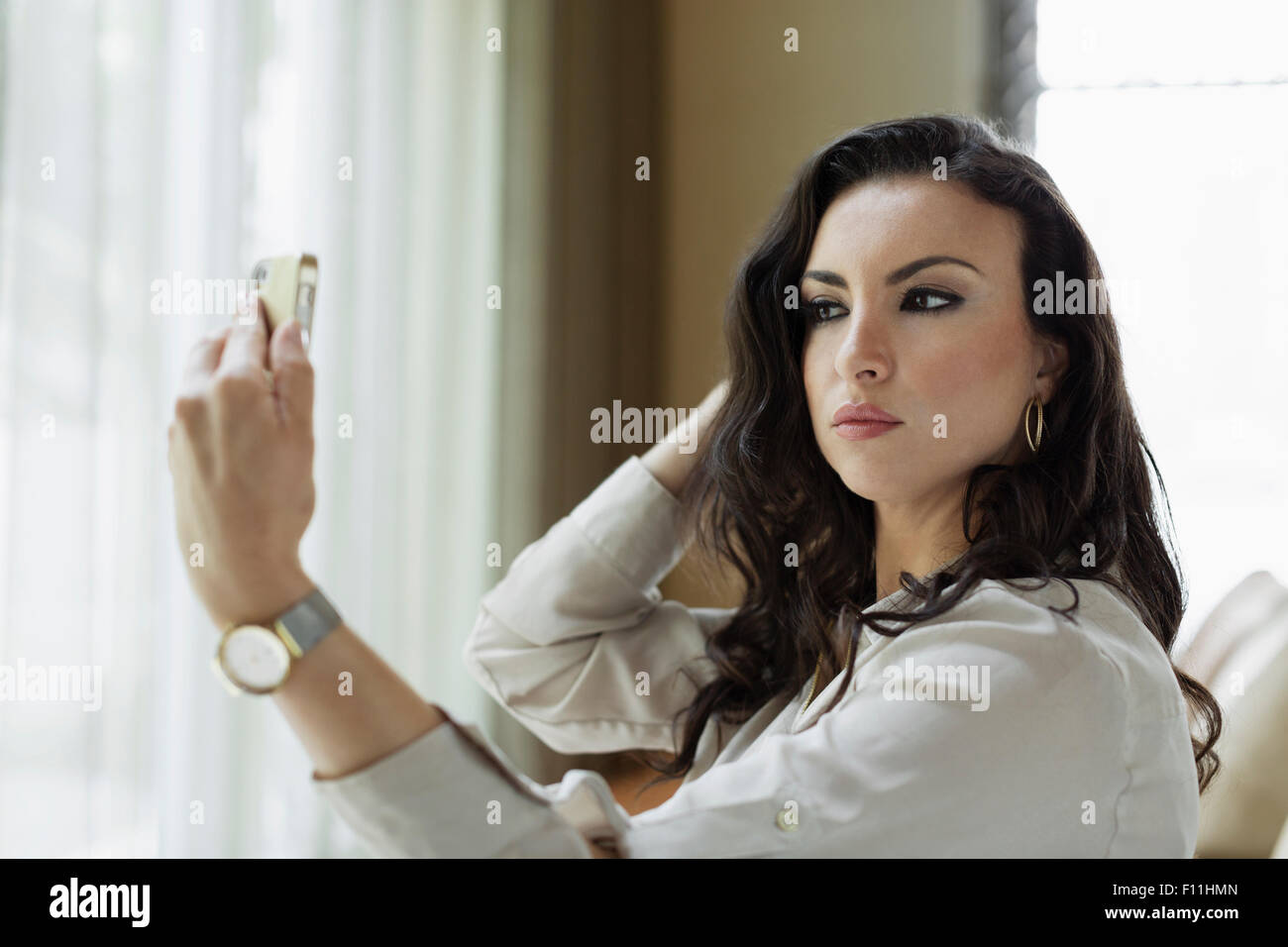 Mixed race businesswoman checking her makeup in hotel lobby Stock Photo
