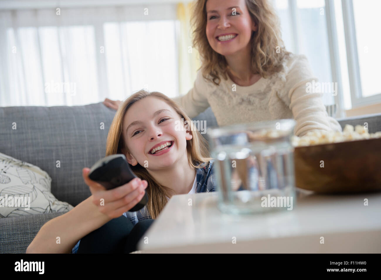 Caucasian mother and daughter watching television on sofa Stock Photo