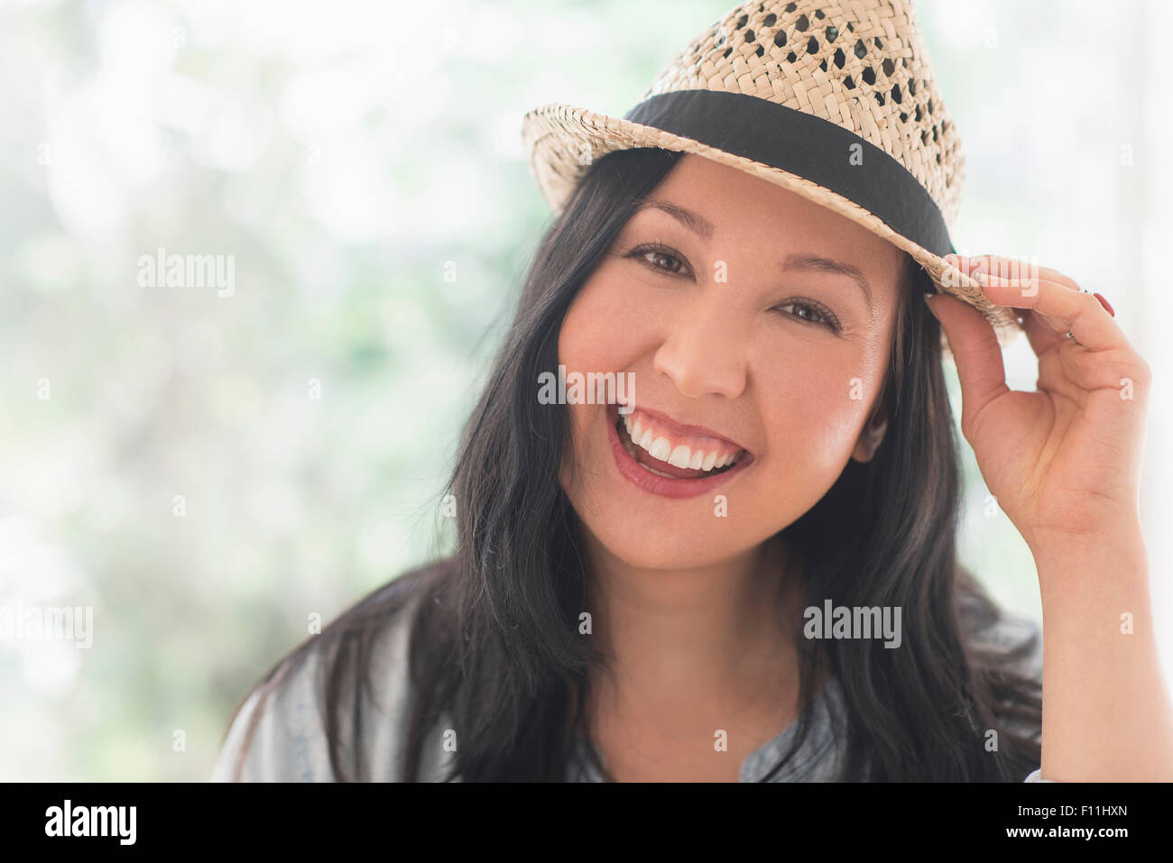 Smiling mixed race woman wearing straw hat Stock Photo
