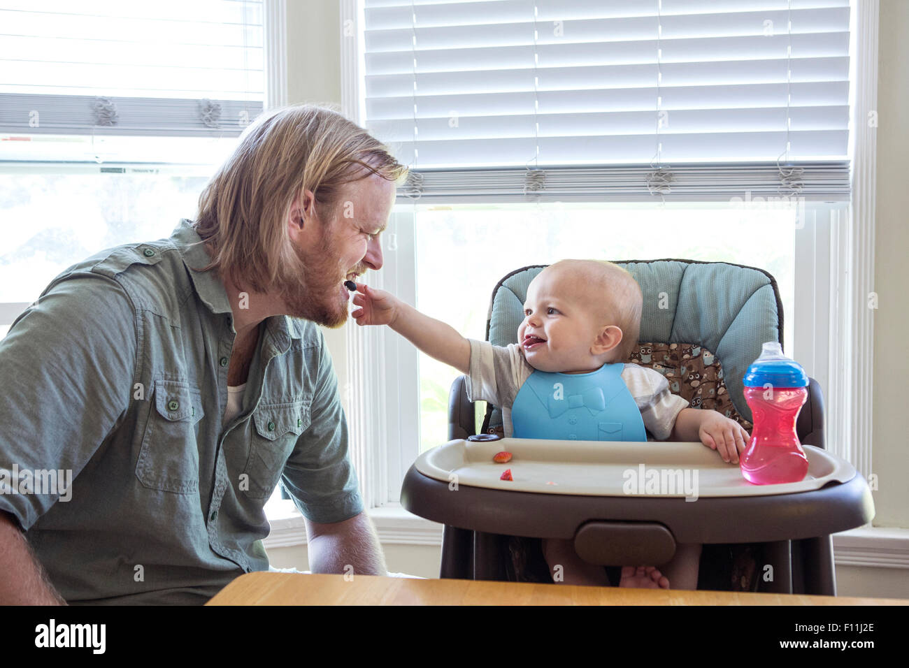 Caucasian father feeding son in high chair Stock Photo