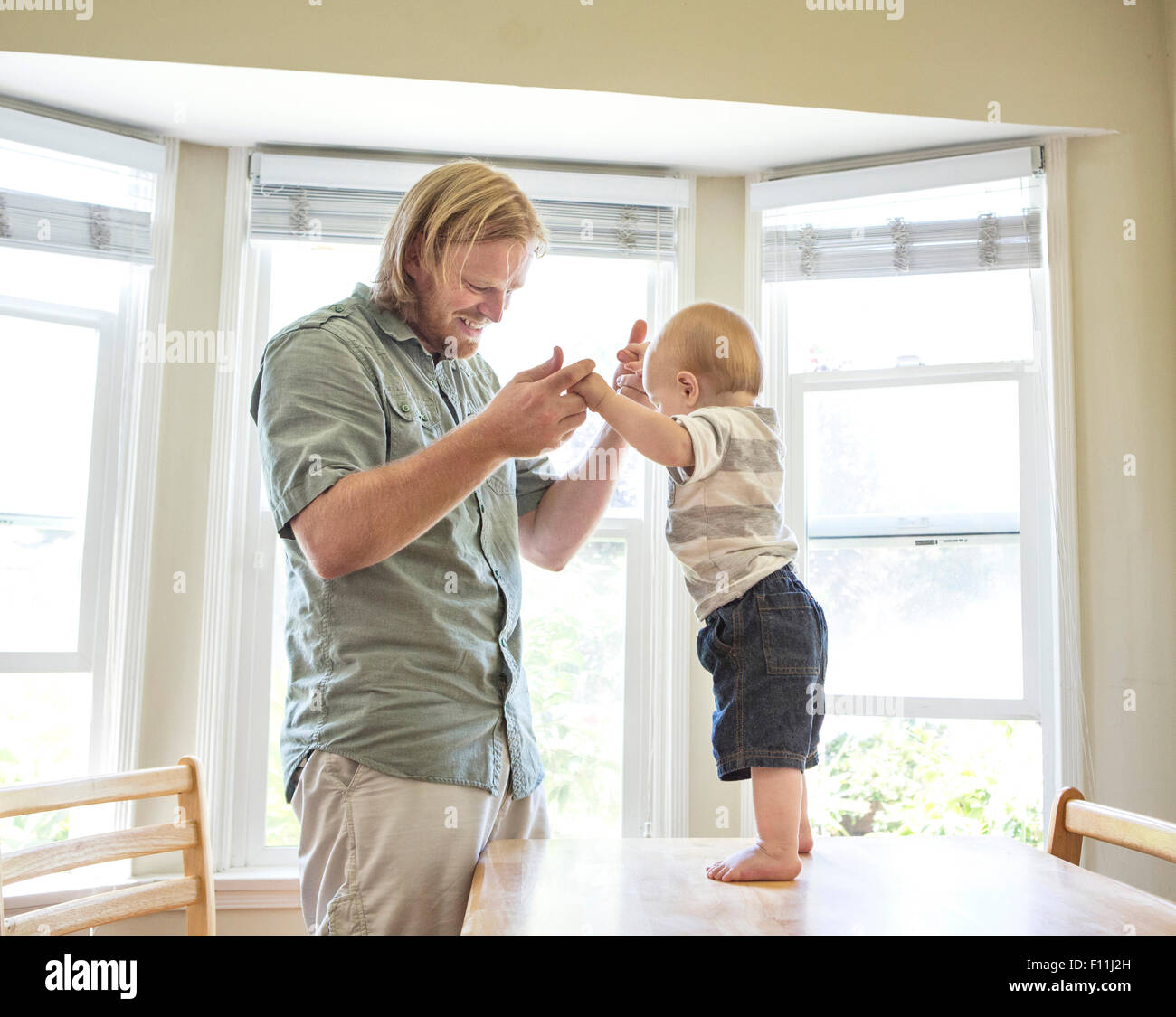 Caucasian father teaching son to stand on table Stock Photo