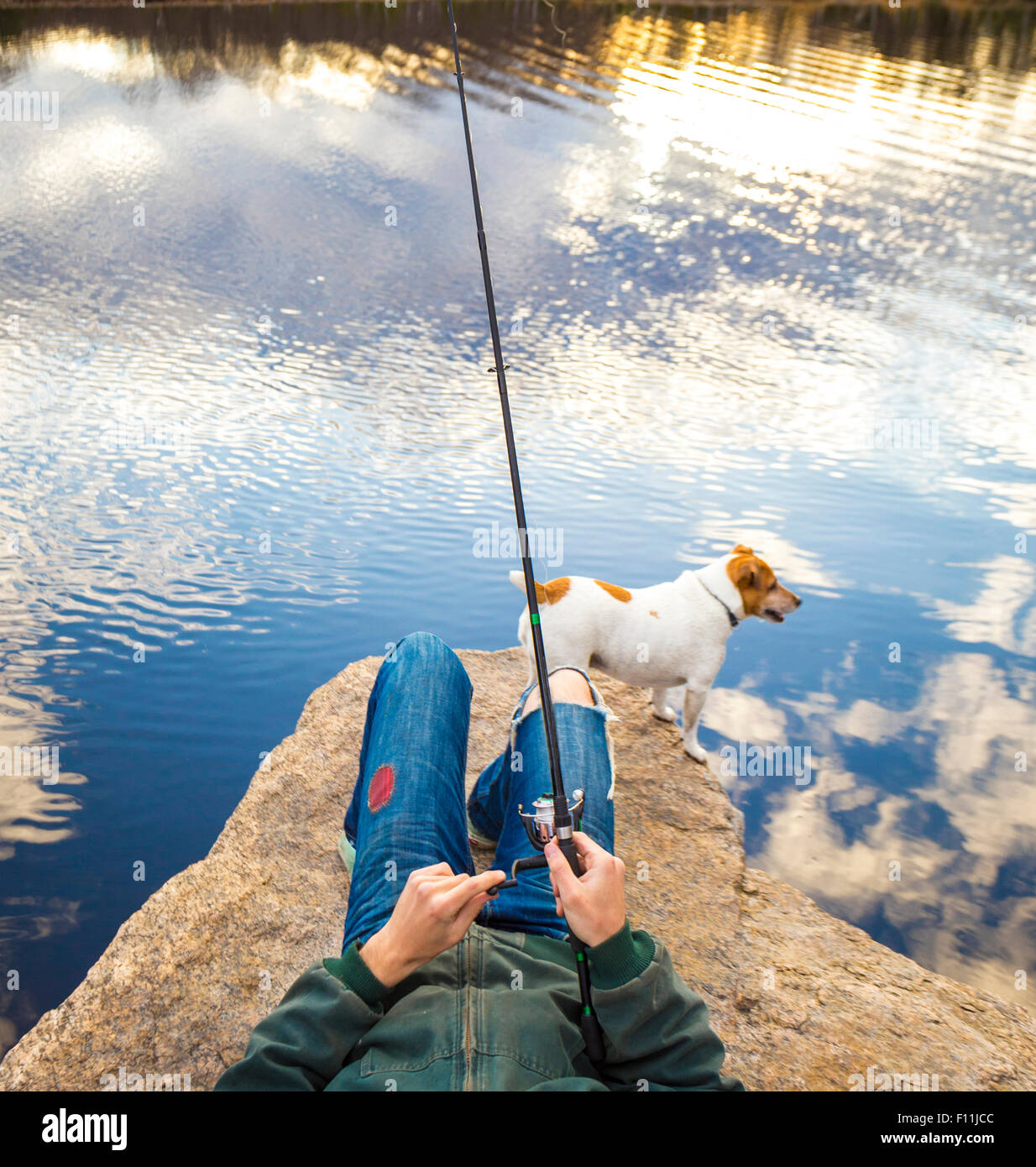 Caucasian man fishing with dog in remote lake Stock Photo