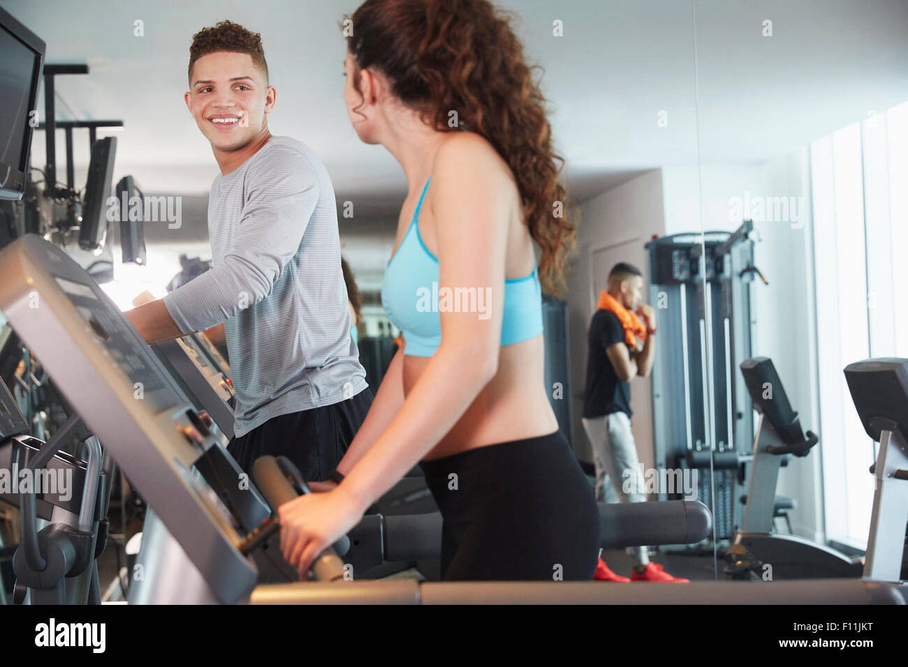 Couple using exercise machines in gym Stock Photo
