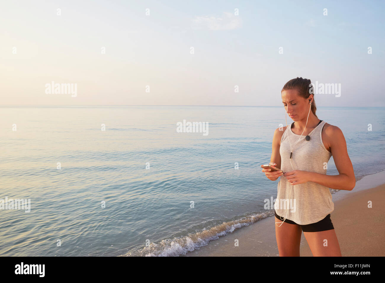 Athlete listening to earphones on beach Stock Photo - Alamy